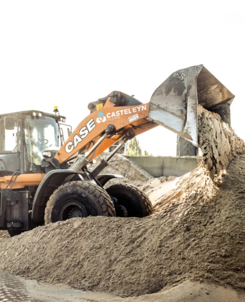 Front loader dumping sand in a construction yard.